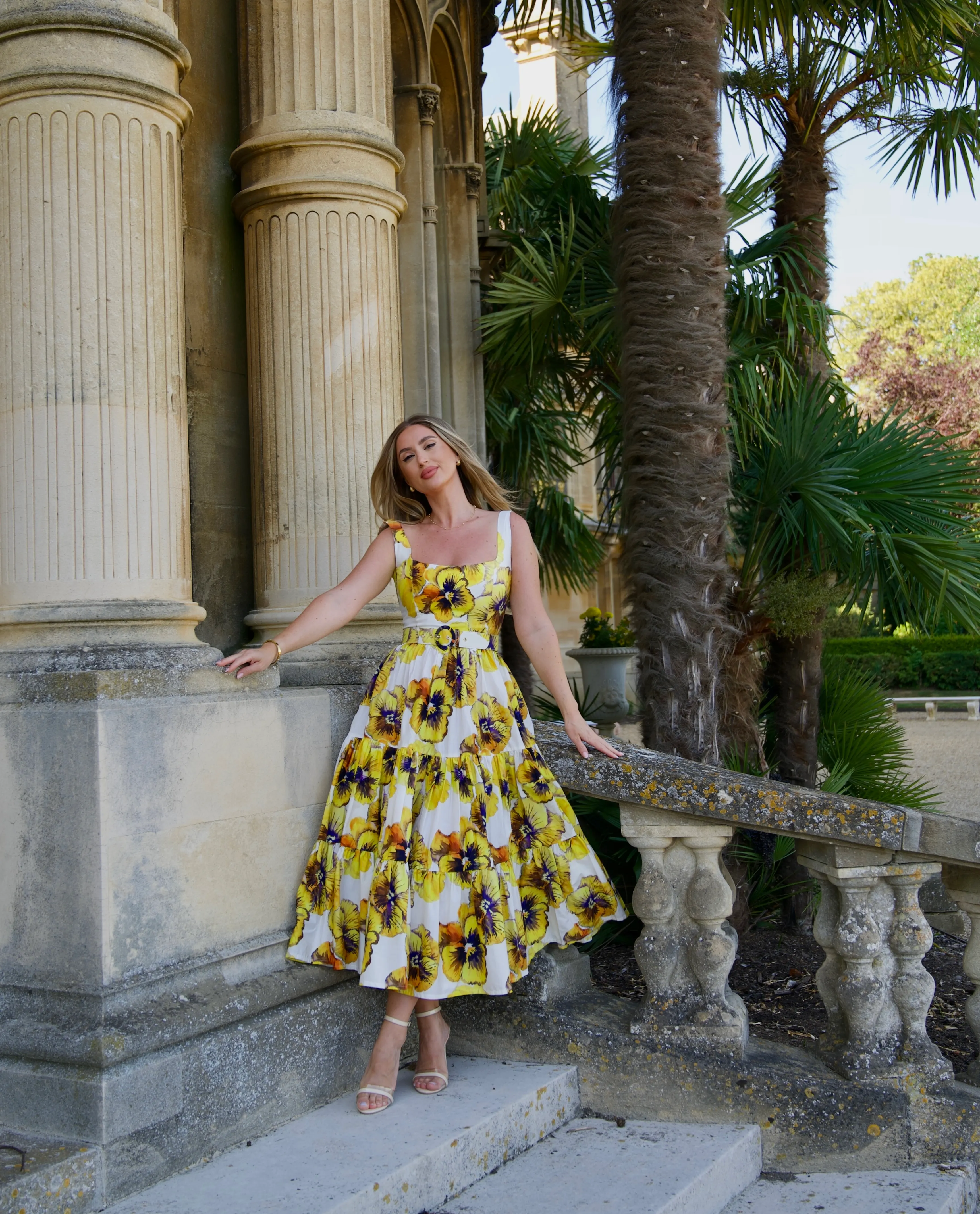 Valentina Fanu wearing a yellow floral summer dress beside stone columns